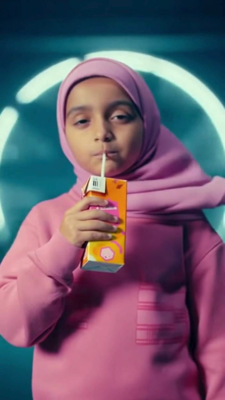 A girl in a pink hoodie and hijab drinks from a juice box in a wind tunnel, from the Bubble Girl Built Different advert